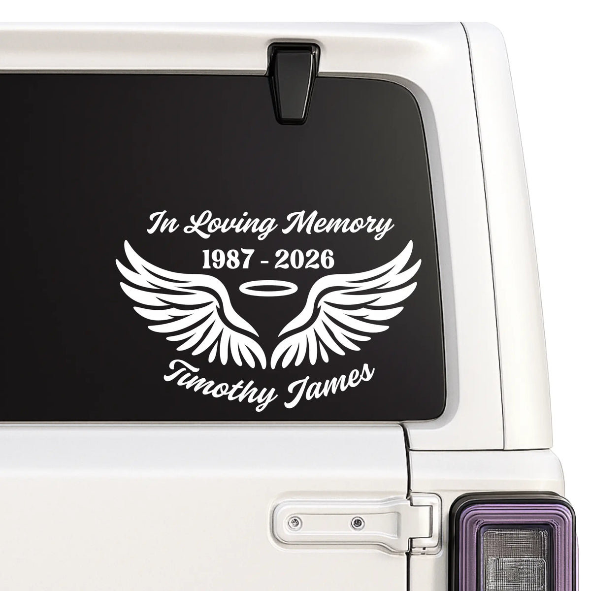 Memorial decal with wings and text on a car window