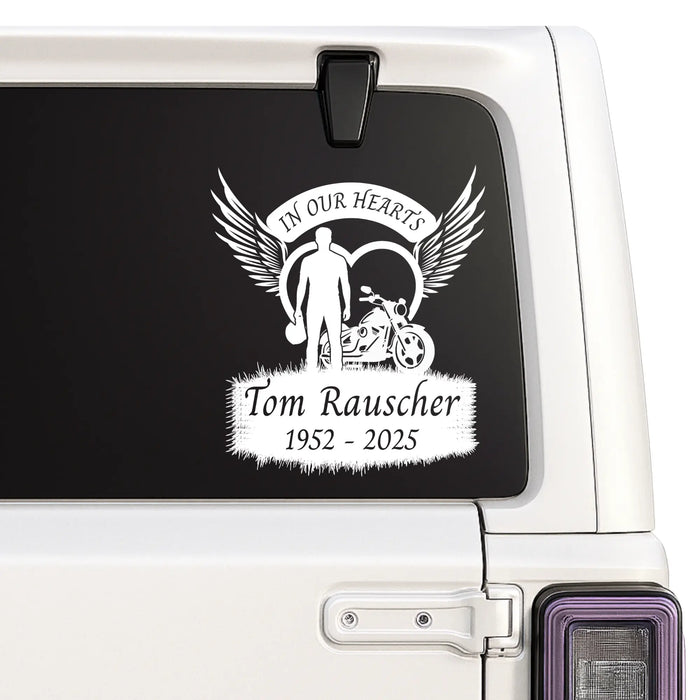 Memorial decal with a motorcycle and text on a car window.