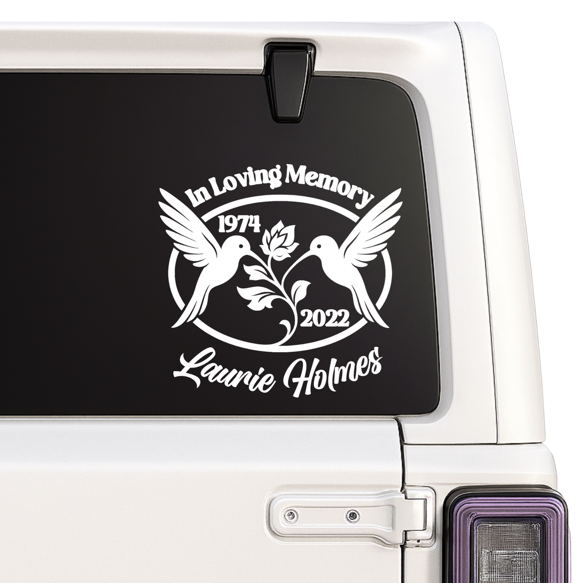 Memorial decal with two birds and text on a car window