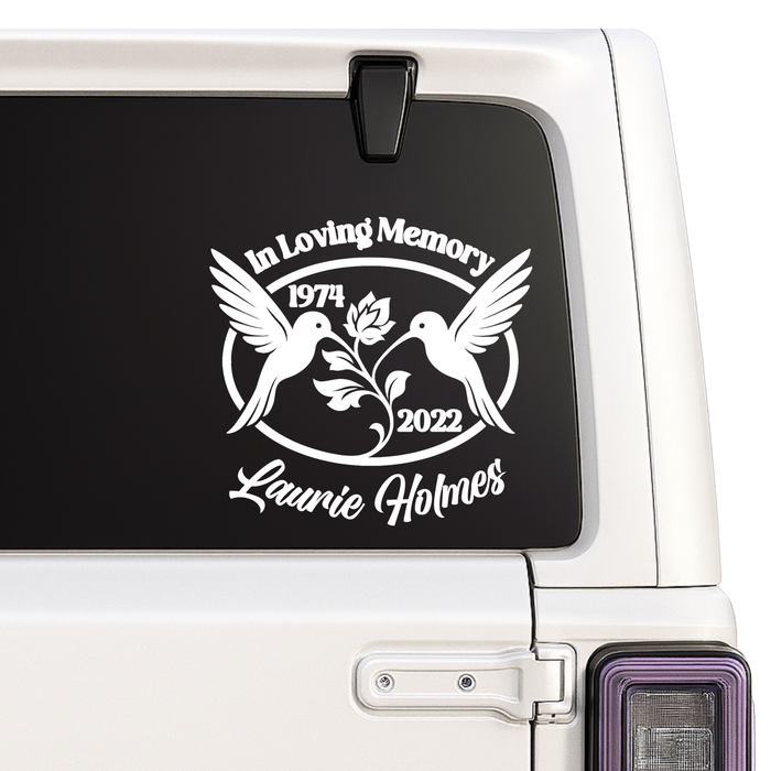Memorial decal with two birds and text on a car window