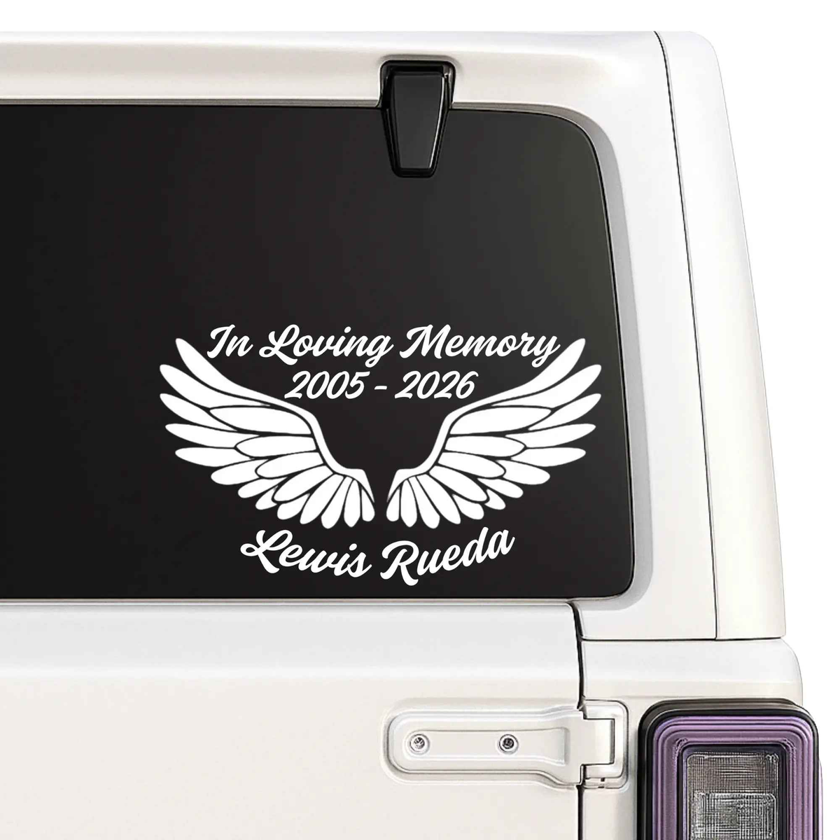 Memorial decal with wings and text on a car window