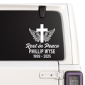 Memorial decal with cross, wings, and text on a vehicle window.