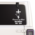 Memorial decal with cross, dove, and text on a vehicle window.