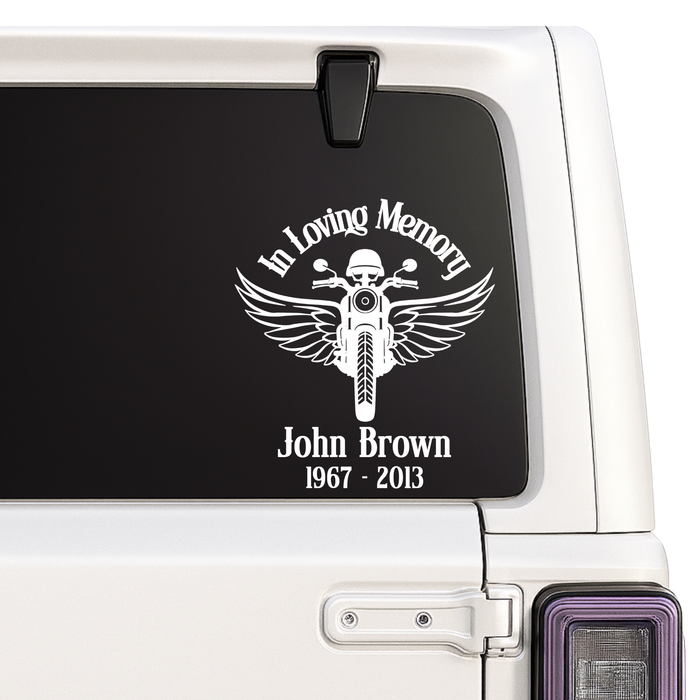Memorial decal with a motorcycle design and text on a car window.