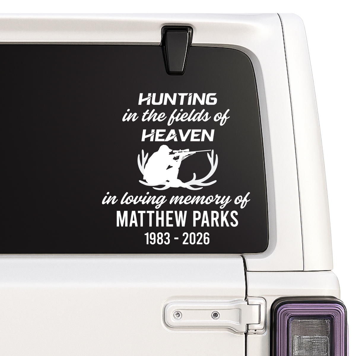 Memorial decal with text and silhouette of a deer on a vehicle window.
