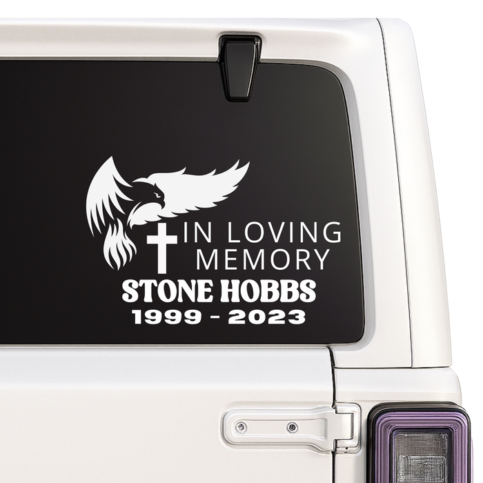 Memorial decal with an eagle, cross, and text on a car window.