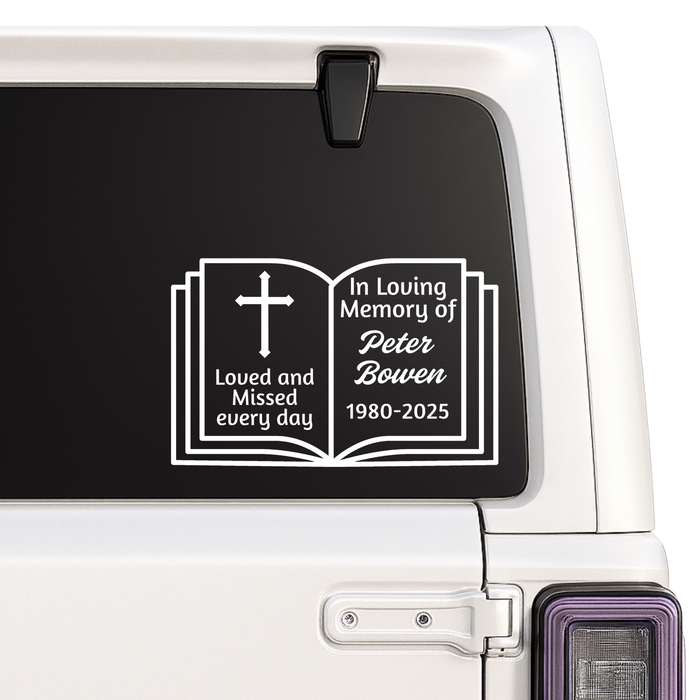 Memorial decal with an open book design on a car window.