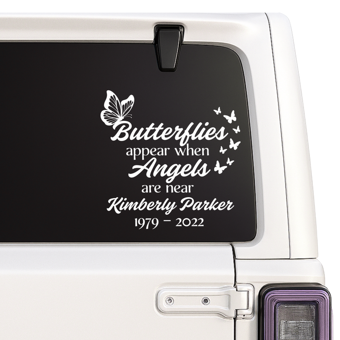 Memorial decal with butterfly design and text on a car window.