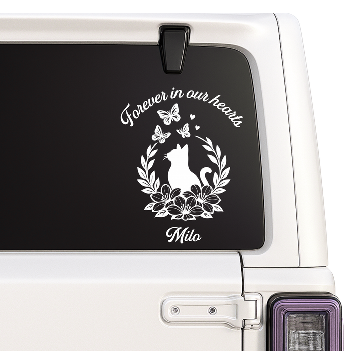 Memorial decal with a cat silhouette and text 'Forever in our hearts Milo' on a vehicle window.