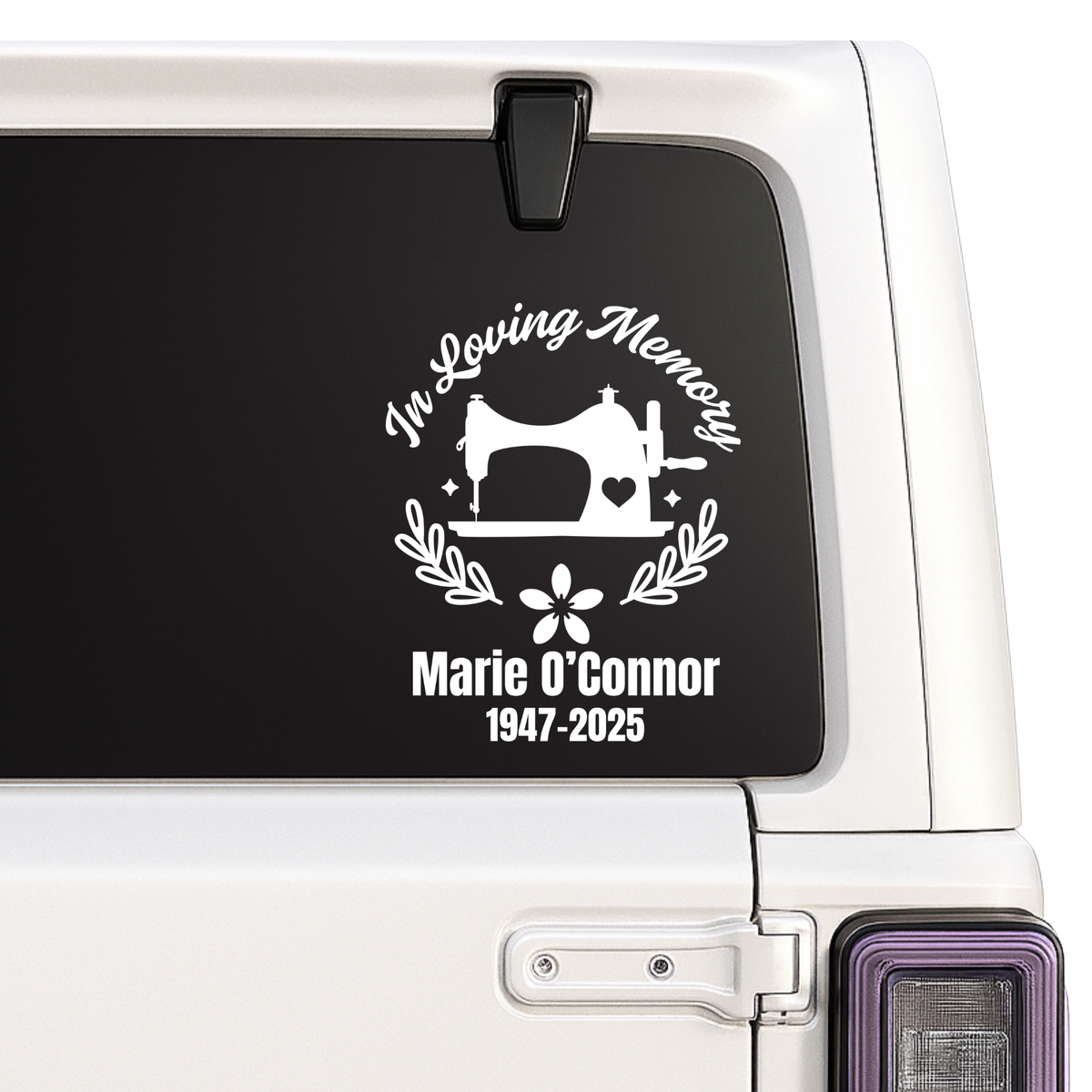 Memorial decal with sewing machine design on a vehicle window.