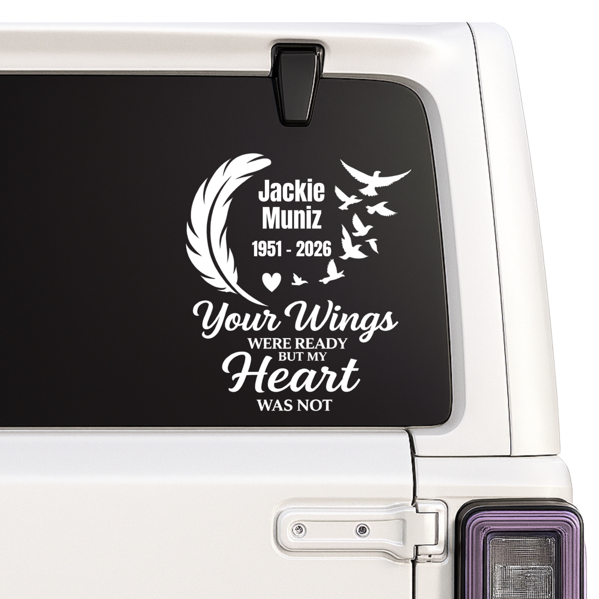 Memorial decal with text and feather design on a vehicle window.