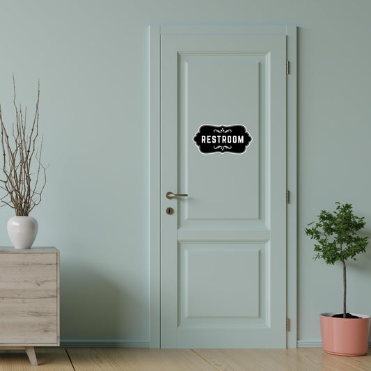 Elegant black vinyl restroom door sign with decorative border, suitable for bathroom decor, by Nostalgi Factory.