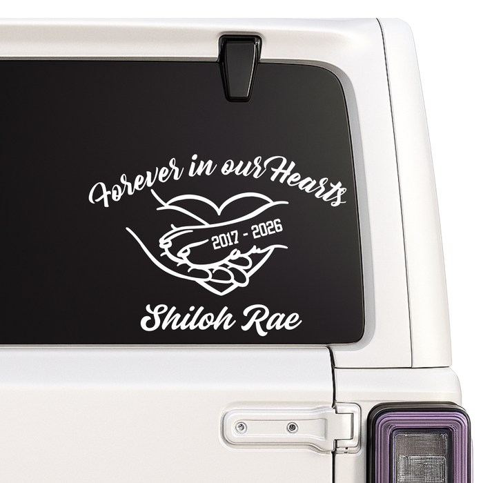 Memorial decal with 'Forever in our Hearts' text on a car window.